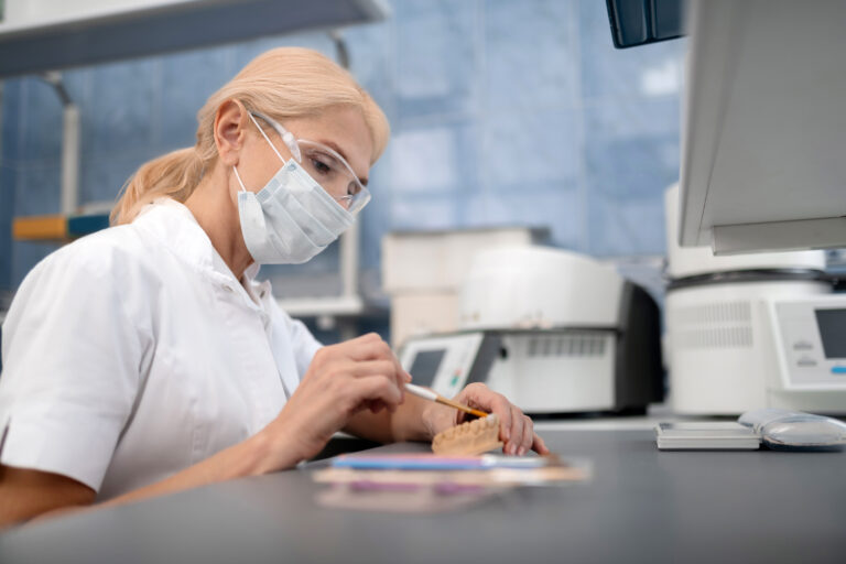 Dental technician making artificial teeth in laboratory